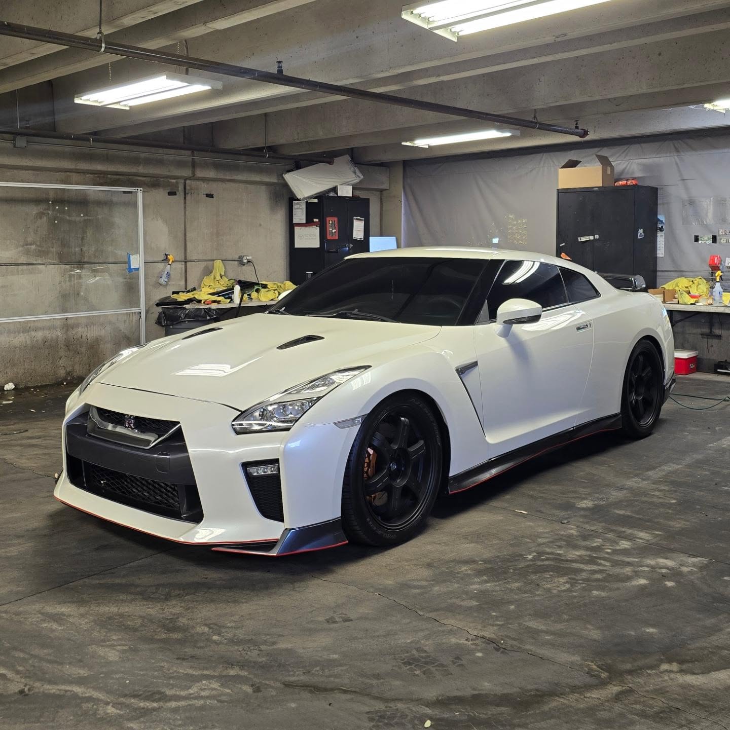 White Nissan GT-R with tinted windows inside an installation area