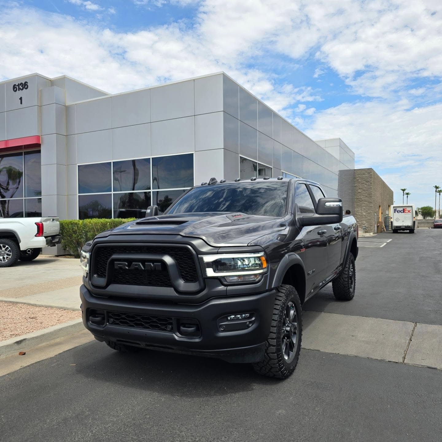 Dark gray Ram pickup with tinted windows outside a dealership
