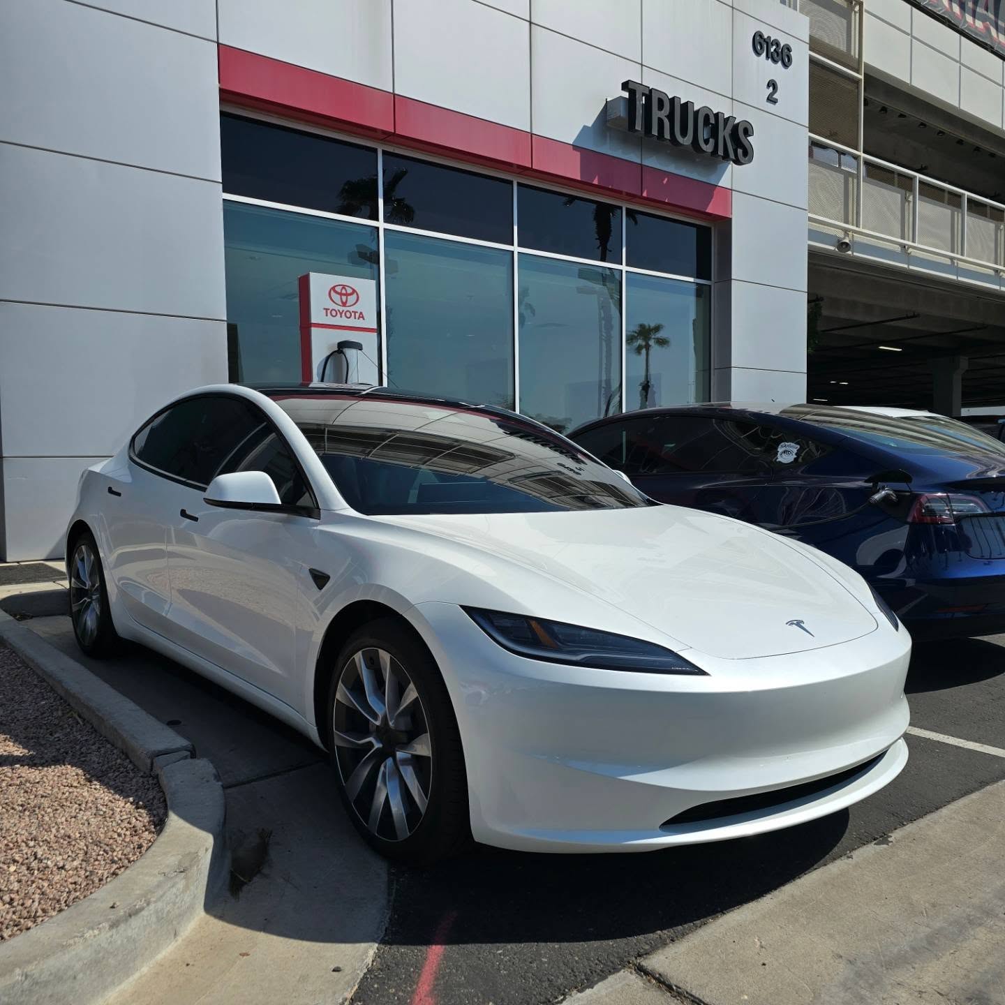 White Tesla Model 3 with tinted windows outside a dealership